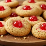 Cherry red dot cookies with vibrant red cherry centers on a rustic wooden plate.